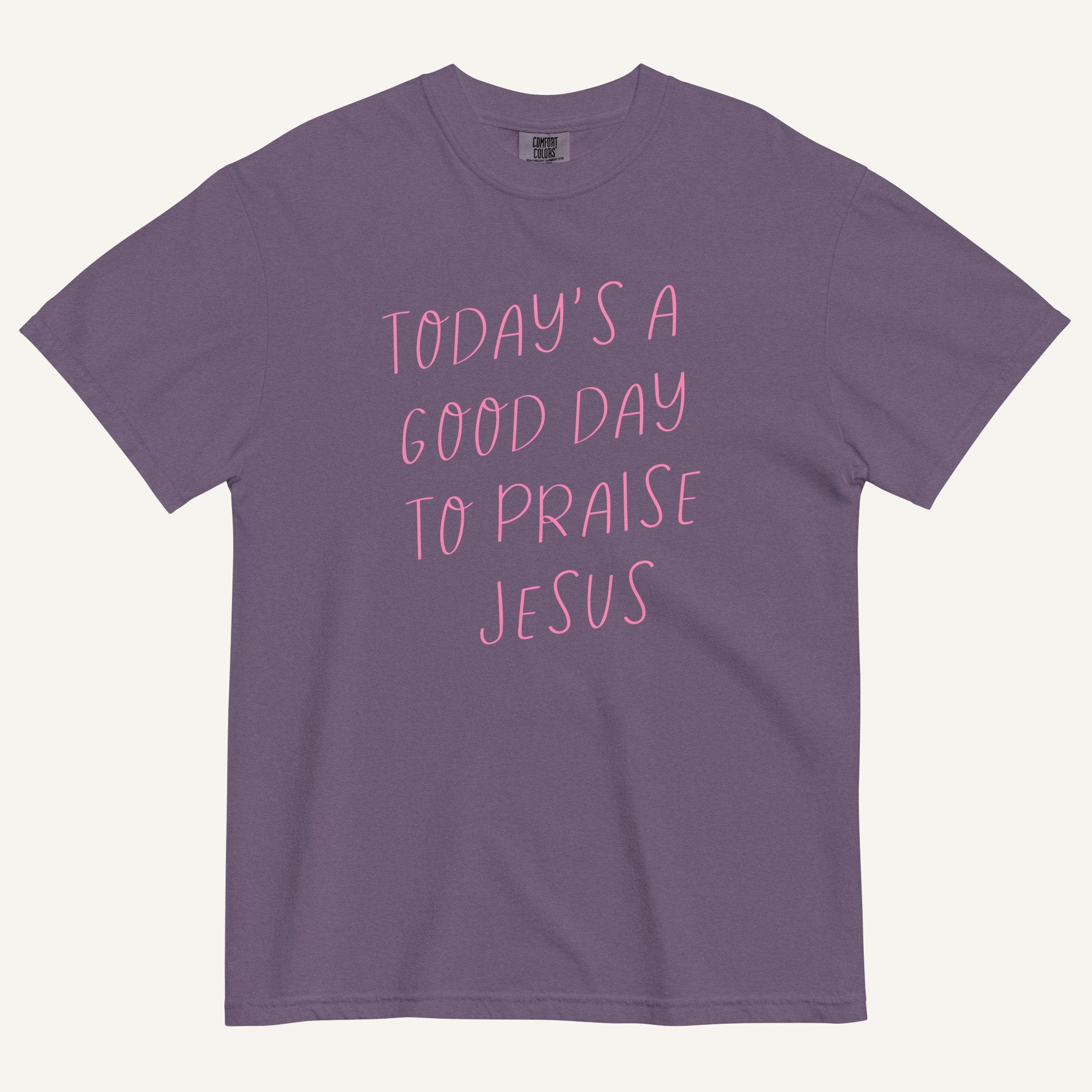 purple t-shirt with 'Today's a Good Day to Praise Jesus' pink text on a cream background
