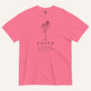 A bright pink short-sleeve crewneck t-shirt with a black line-art mustard seed graphic and the text 'FAITH as small as a mustard seed' and 'MATTHEW 17:20' printed on the front, displayed against a light cream background.