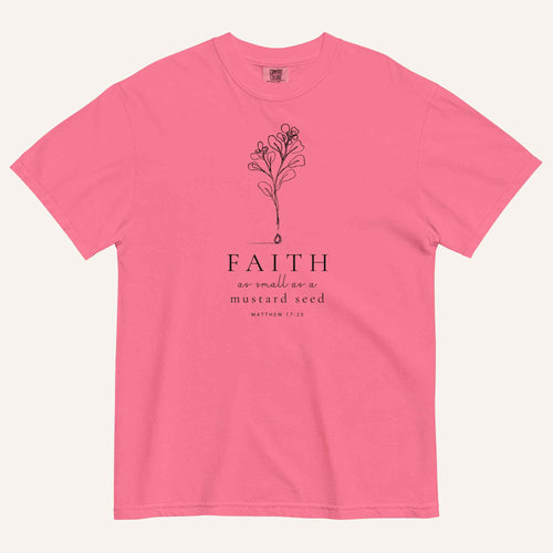 A bright pink short-sleeve crewneck t-shirt with a black line-art mustard seed graphic and the text 'FAITH as small as a mustard seed' and 'MATTHEW 17:20' printed on the front, displayed against a light cream background.