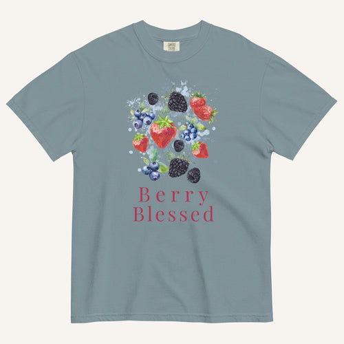 A slate blue crewneck t-shirt featuring a watercolor graphic of strawberries, blueberries, and blackberries with the text 'Berry Blessed' printed below in berry red, displayed on a light cream background.