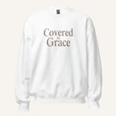 white sweatshirt with 'Covered in Grace' text on a cream background