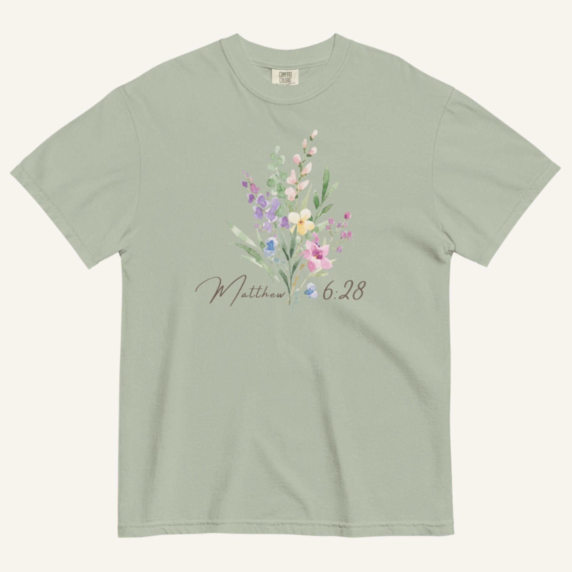 Green t-shirt with floral design and 'Matthew 6:28' text on a white background