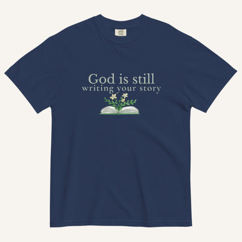 navy blue t-shirt with 'God is still writing your story' text and book graphic on a white background