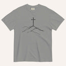A gray short-sleeve crewneck t-shirt featuring a minimalist black line art graphic of a cross rising from simple hills on the chest, displayed flat against a light off-white background.