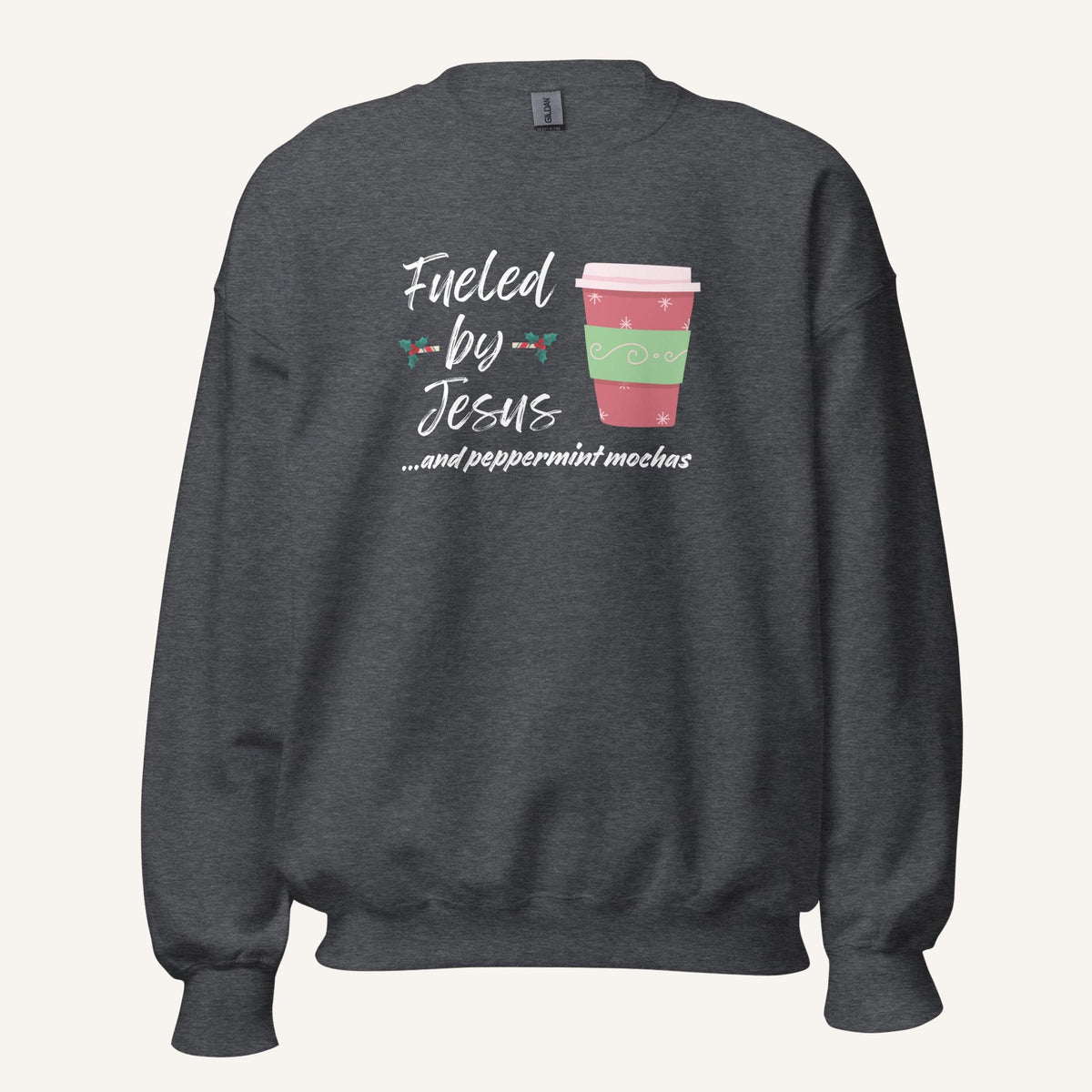 Grey unisex crewneck sweatshirt featuring a Christmas design with the phrase “Fueled by Jesus …and peppermint mochas,” peppermint illustrations, and a festive red and green peppermint mocha cup graphic.