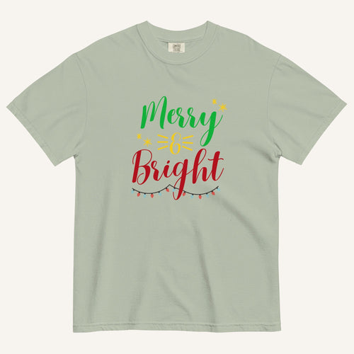 a muted sage green t-shirt that has "Merry & Bright" colored text with Christmas lights and star graphics