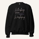 Black crewneck sweatshirt with "Whisking while Worshiping" pink text with a pink whisk graphic.