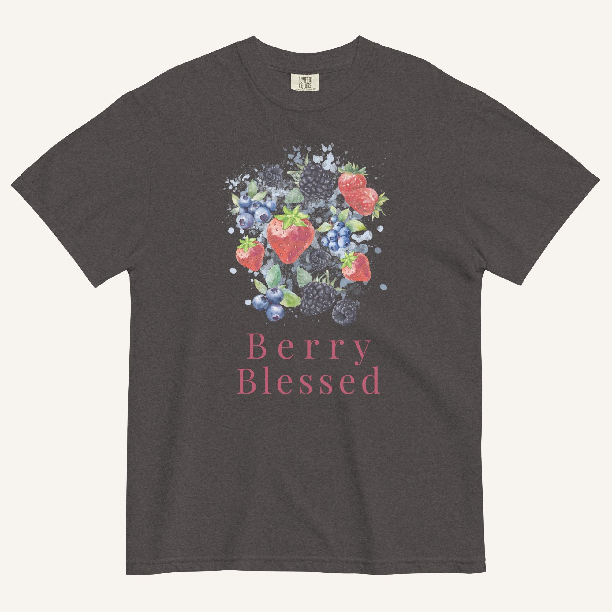 A dark charcoal gray t-shirt featuring a colorful watercolor graphic of strawberries, blueberries, and blackberries with the text 'Berry Blessed' printed below in pink, displayed against a light cream background.