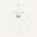white t-shirt with 'God is still writing your story' text and book graphic on a white background