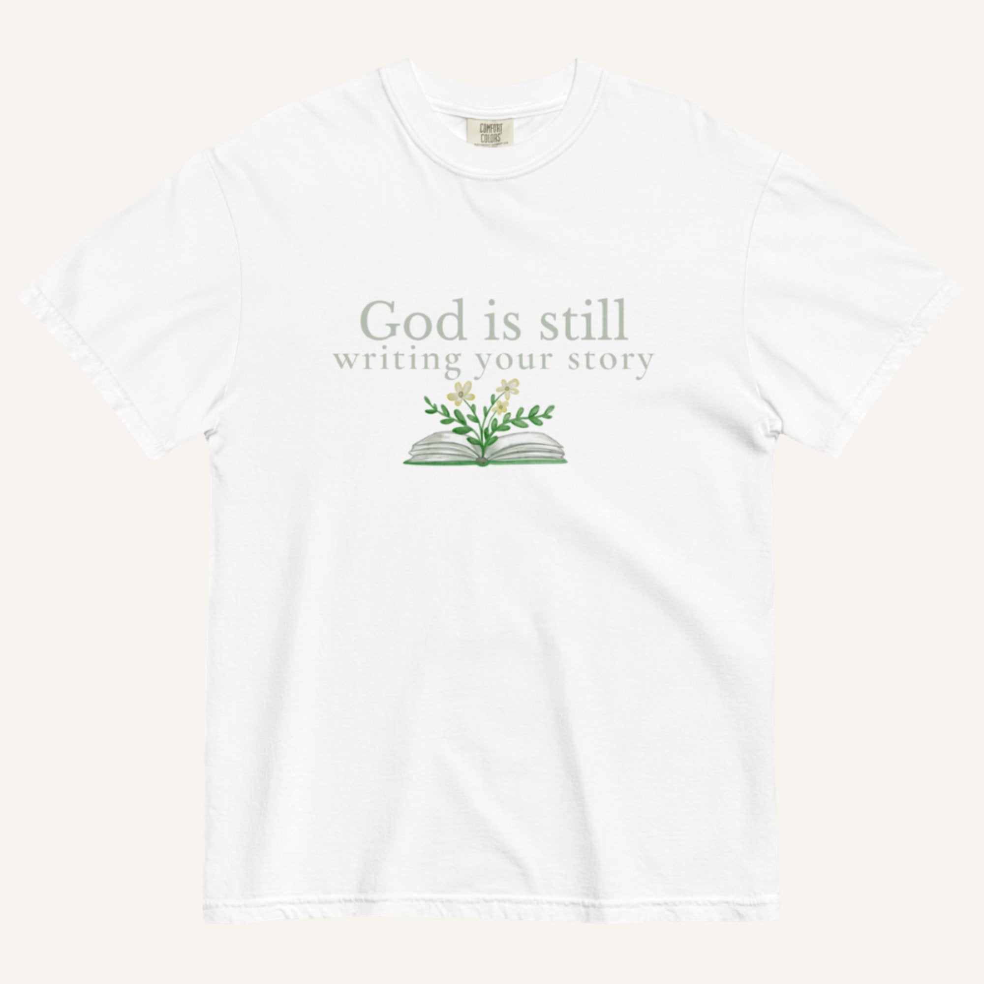 white t-shirt with 'God is still writing your story' text and book graphic on a white background