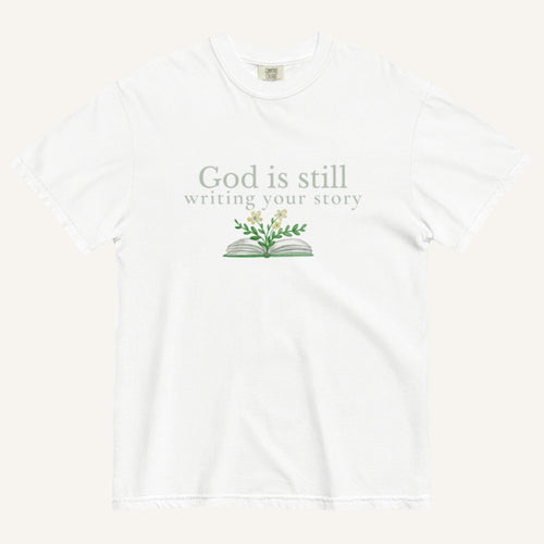 white t-shirt with 'God is still writing your story' text and book graphic on a white background