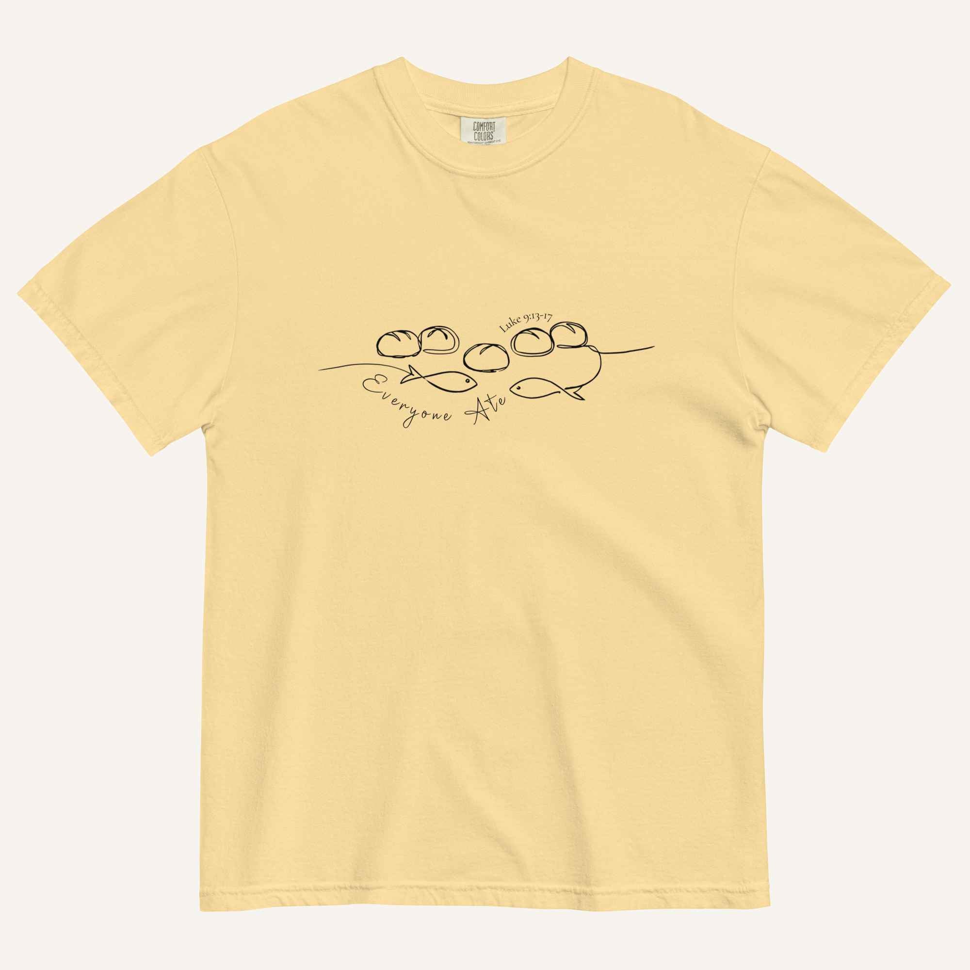 A yellow short-sleeve crewneck t-shirt with a black graphic of two fish and 5 loaves of bread on a line and the cursive text 'Everyone Ate' across the chest, displayed flat against a light beige background.