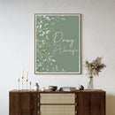 'Pray Always' text with green botanical within a frame hanging on a wall in a neutral living room