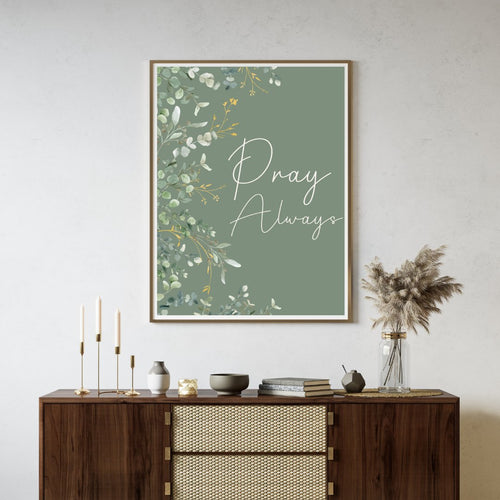 'Pray Always' text with green botanical within a frame hanging on a wall in a neutral living room