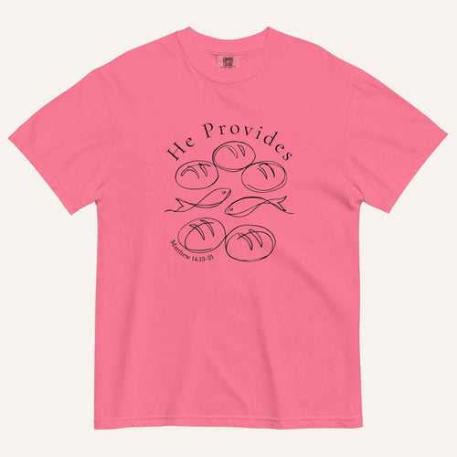 A bright pink short-sleeve t-shirt with a black graphic print on the front showing fish and loaves of bread, with the text 'He Provides' and 'Matthew 14:13-21'.