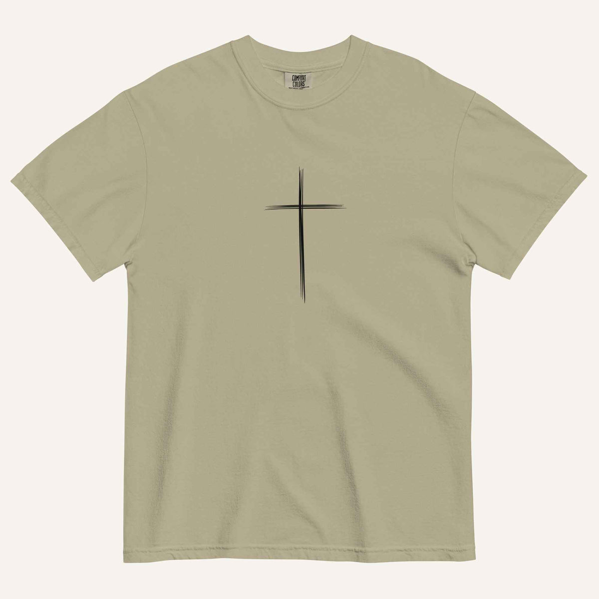A short-sleeve crewneck t-shirt in a light olive green color, featuring a simple black Christian cross printed on the center chest. The t-shirt is laid flat against a solid, warm off-white background.