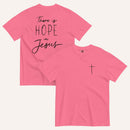 A pink t-shirt shown from both the front and back. The front features a small black cross on the top left. The back features the black text 'There is HOPE in Jesus' in a mix of script and block lettering.