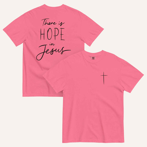 A pink t-shirt shown from both the front and back. The front features a small black cross on the top left. The back features the black text 'There is HOPE in Jesus' in a mix of script and block lettering.