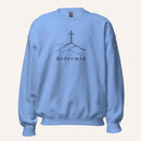 A light blue crewneck sweatshirt featuring a black graphic of a cross on a hill with the word 'Redeemed' printed below it, displayed on a clean off-white background.
