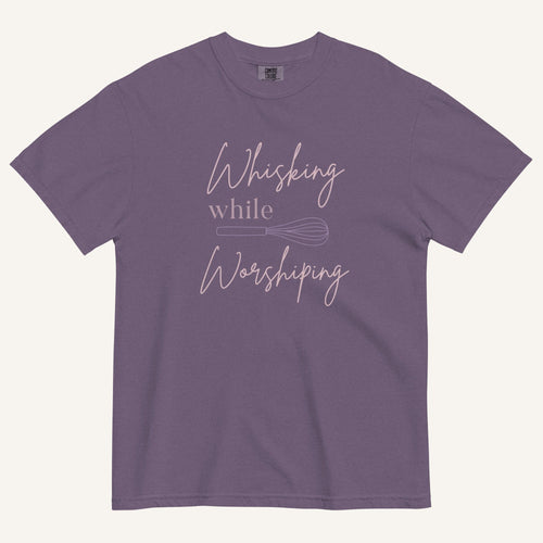 purple t-shirt with "Whisking while worshiping" text and a whisk graphic