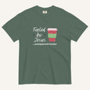 Blue spruce Christmas T-shirt featuring the phrase “Fueled by Jesus …and peppermint mochas” with a festive peppermint mocha cup design.