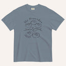 A muted blue short-sleeve t-shirt with a black graphic print on the front showing fish and loaves of bread, with the text 'He Provides' and 'Matthew 14:13-21'.