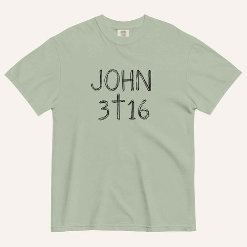 A sage green short-sleeve crewneck t-shirt with 'JOHN 3 16' text with cross graphic in between the 3 & 16 printed in a black hand-drawn font on the chest, displayed flat against a light cream background.