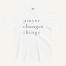 White t-shirt with 'prayer changes things' text in purple on a white background