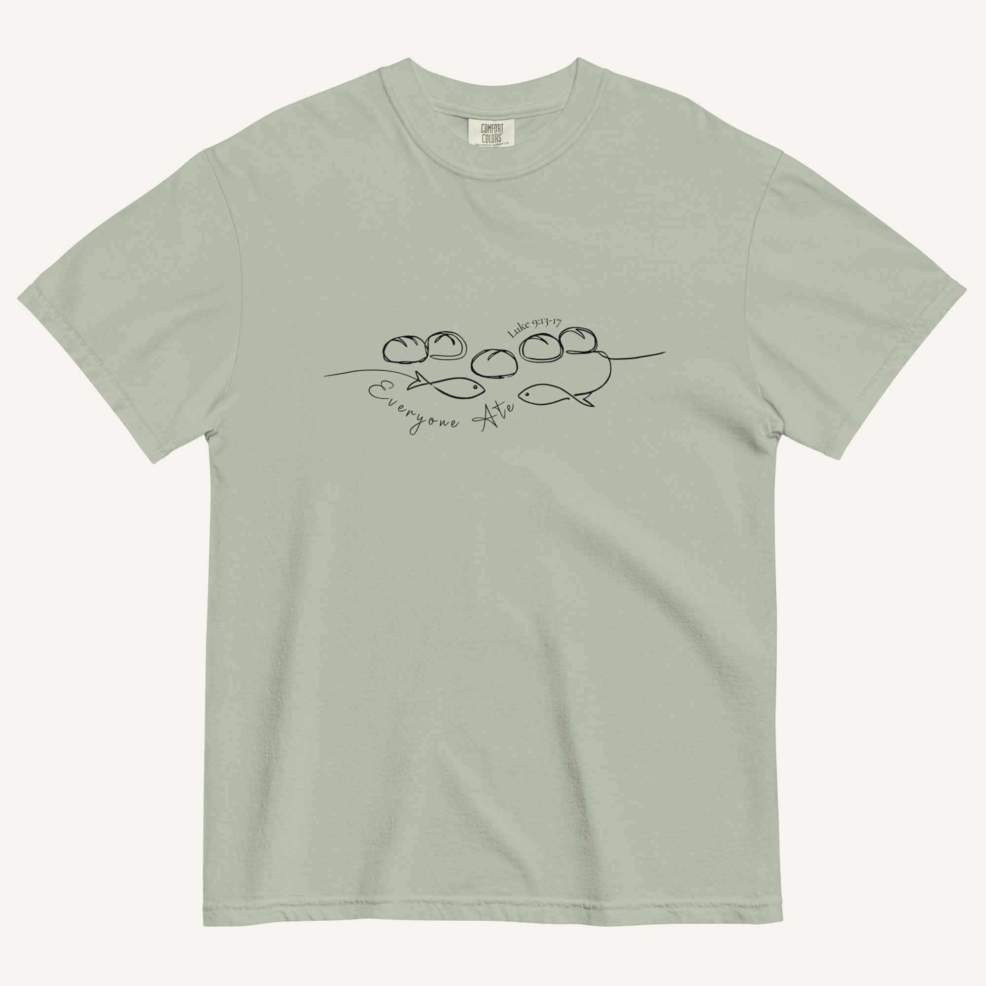 A sage green short-sleeve crewneck t-shirt with a black graphic of two fish and 5 loaves of bread on a line and the cursive text 'Everyone Ate' across the chest, displayed flat against a light beige background.