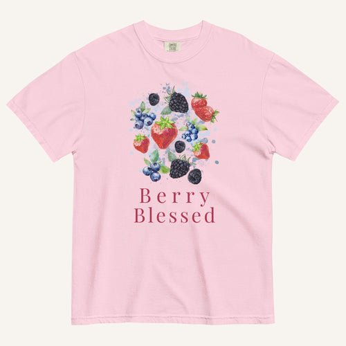 A light pink short-sleeve crewneck t-shirt featuring a colorful watercolor graphic of various berries (strawberries, blueberries, blackberries) and the text 'Berry Blessed' printed below it, displayed on a clean off-white background.