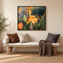 an orange flower in a frame in a living room hanging on the wall above a couch