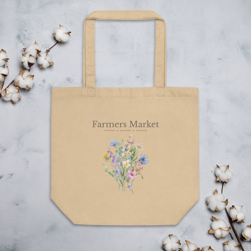 Beige tote bag with floral design and 'Farmers Market' text on a light gray background with cotton branches.