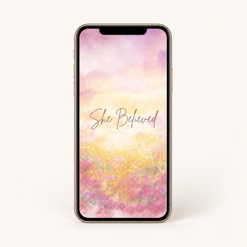 Smartphone with a floral design and 'She Believed' text on a white background